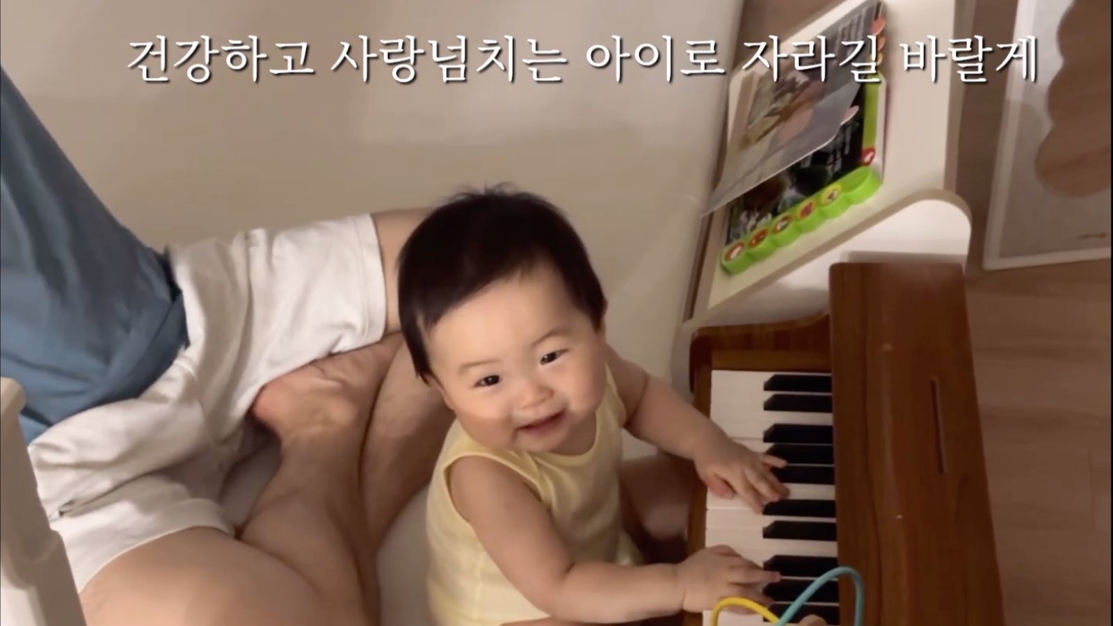 돌잔치 성장영상 장면 — 피아노 앞에 앉은 돌 무렵의 아기